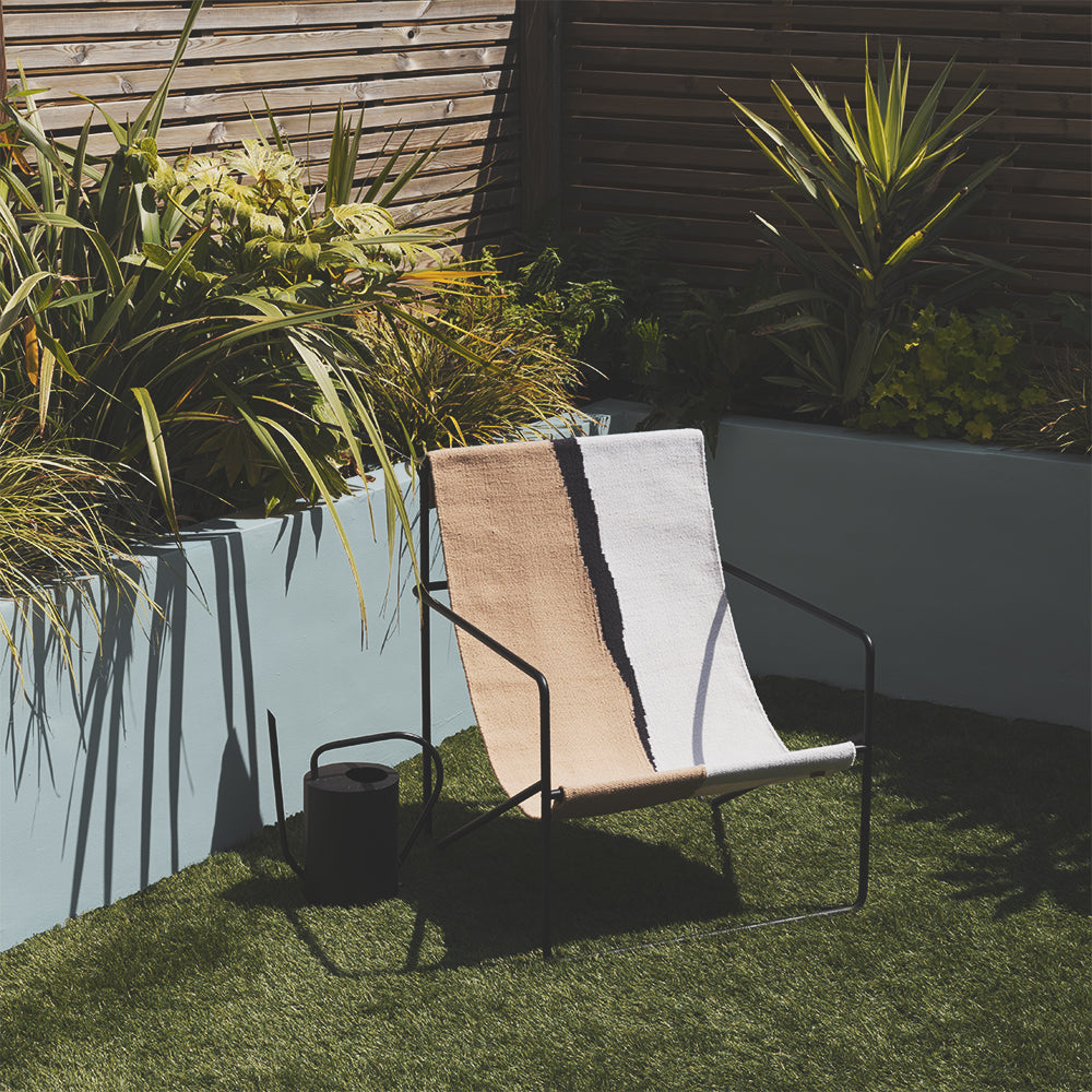 Garden wall painted in Lie-in exterior paint by COAT Paints, a soft grey-blue, with patio chair and plants
