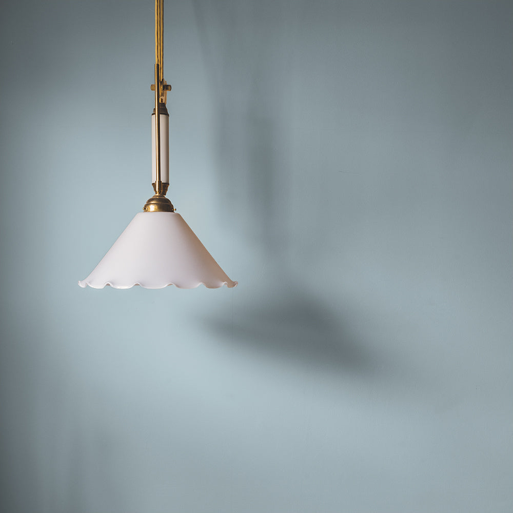 Pendant light against a soft grey-blue wall painted in Lie-in by COAT Paints